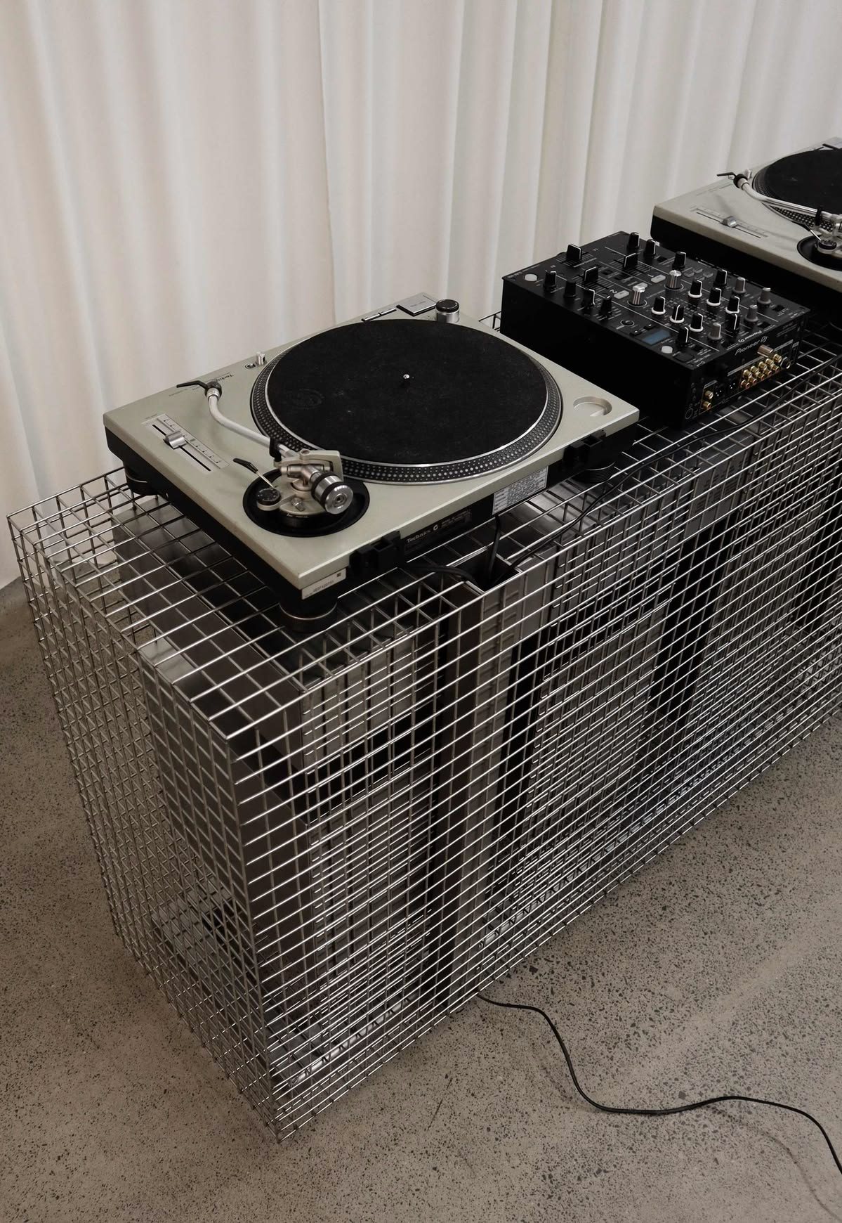Turntables and a mixer on a steel mesh plinth
