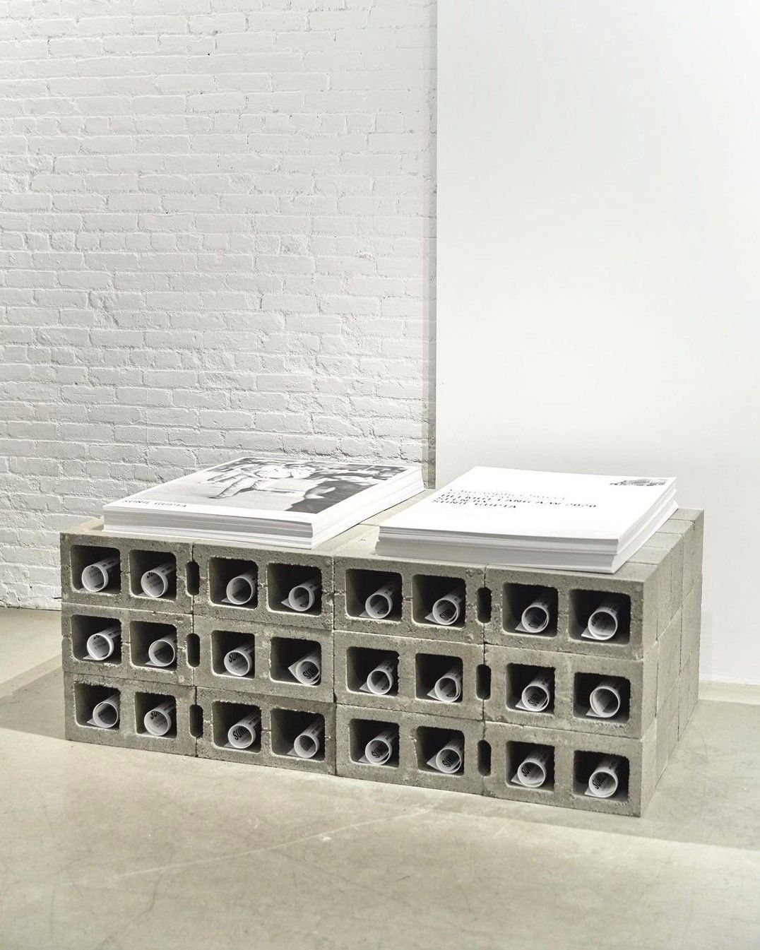 Stacks of prints resting on a low shelf of breeze blocks