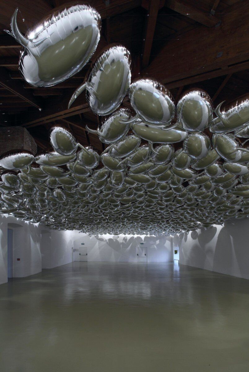 Hundreds of silver inflatables clustered across a ceiling