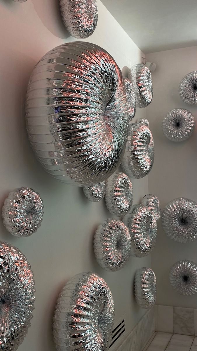 Silver inflated rings mounted across a white wall