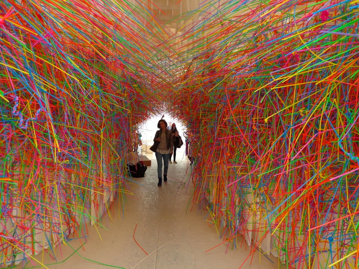 Visitors walking through a tunnel of thousands of coloured strands