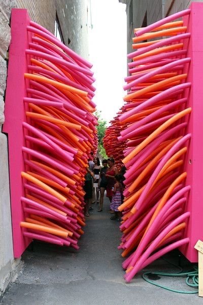 Walls of stacked pink and orange tubes forming a narrow passage