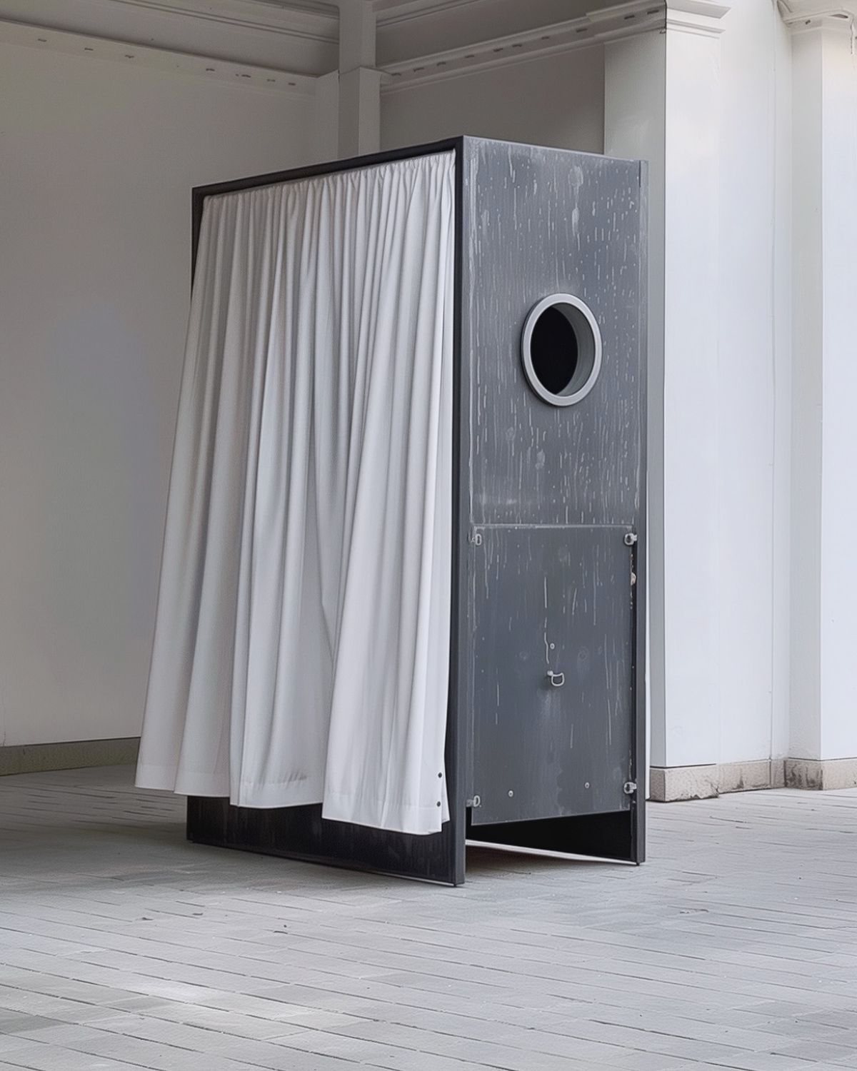 A metal booth with a porthole window and a white curtain for a door